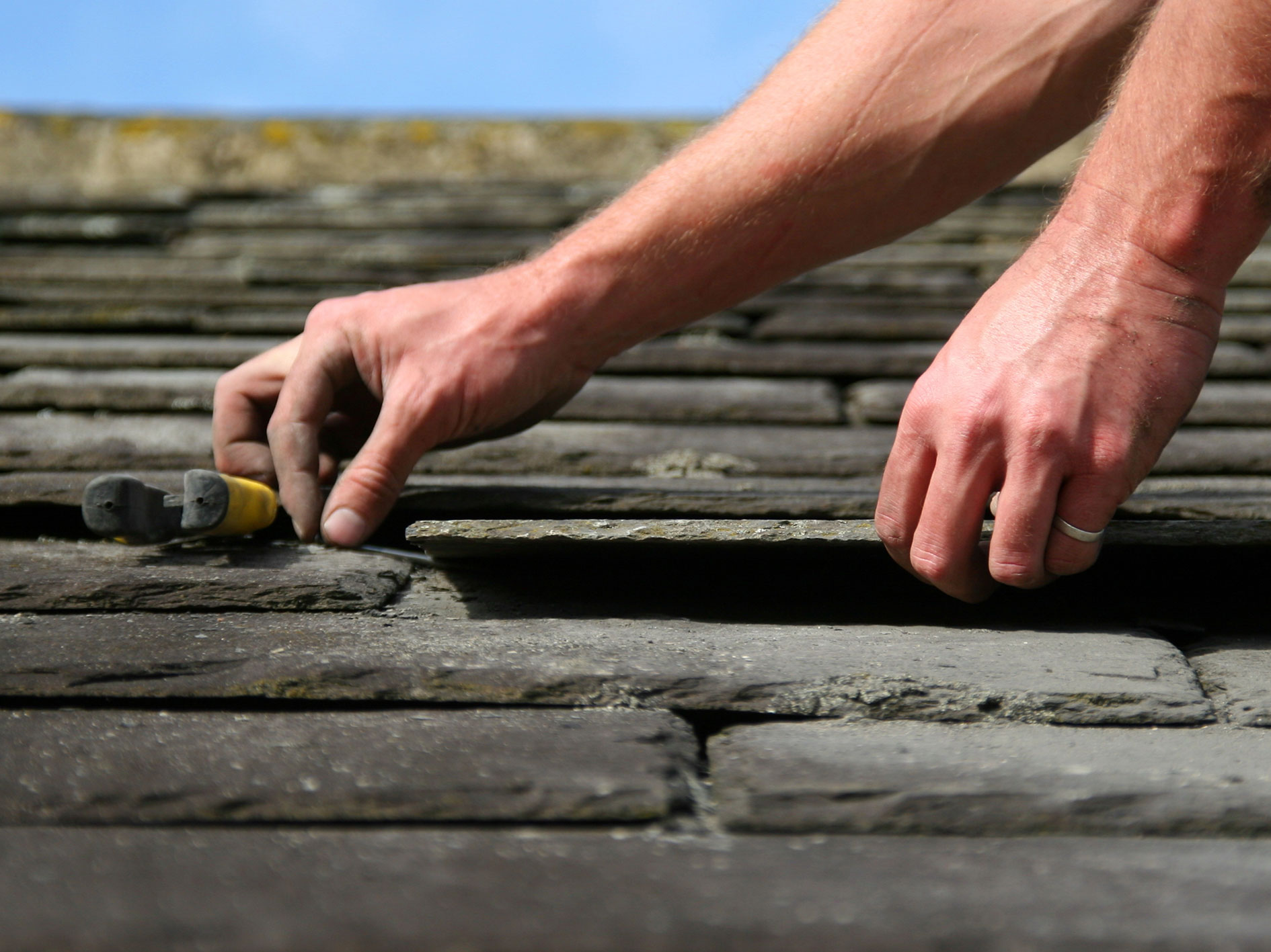 Worker laying down slates on a roof